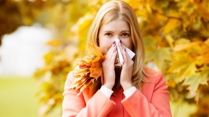 Girl with cold rhinitis on autumn background. Fall flu season. Ill sick sneezing woman. Handkerchief, vaccine against influenza virus Caught Cold Headache Allergy runny nose